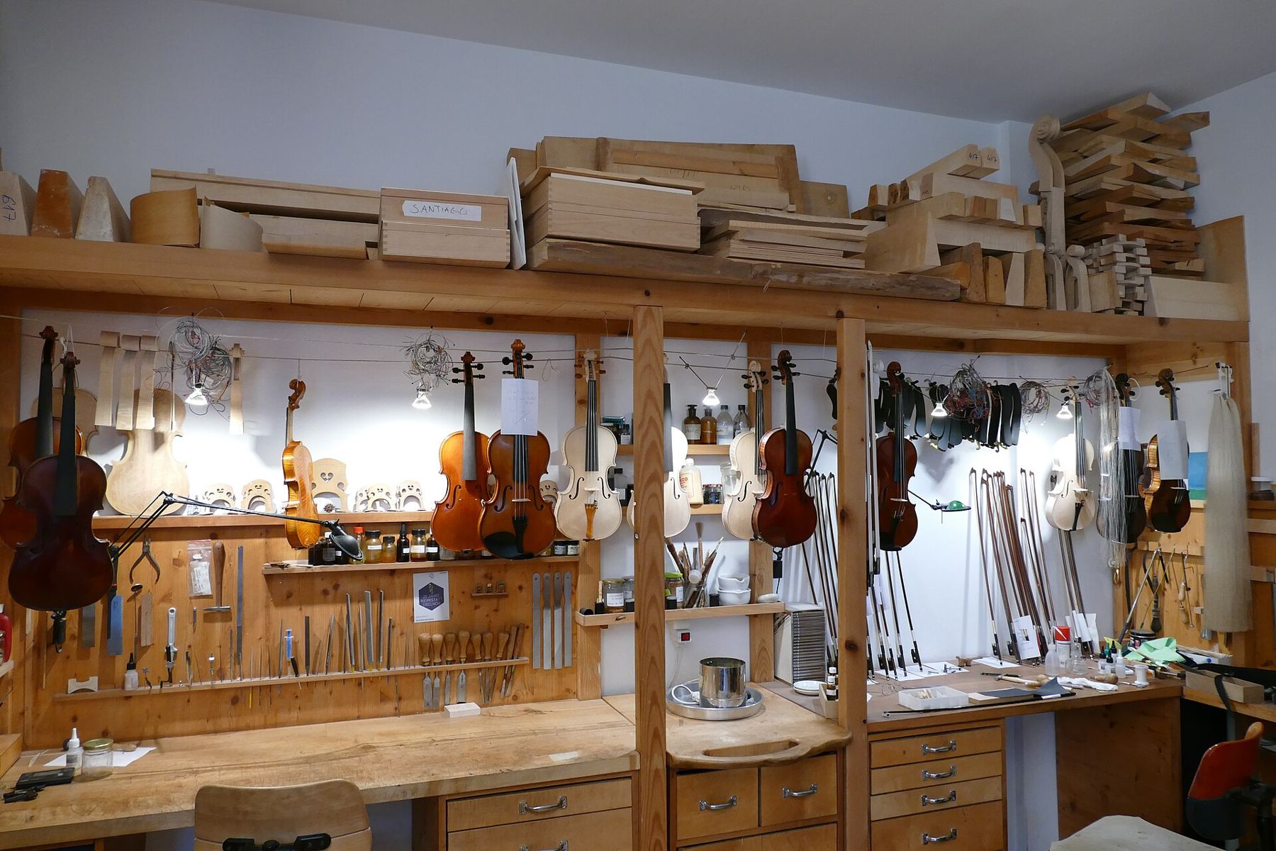 A tidy luthier workshop with shelves of tools and instruments in progress