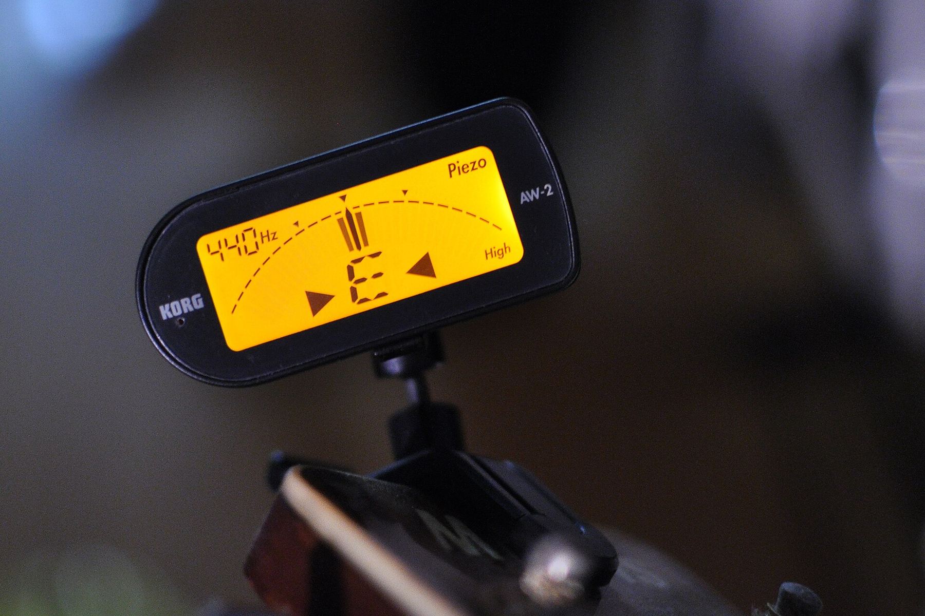 A clip-on tuner with a bright yellow display attached to a guitar headstock