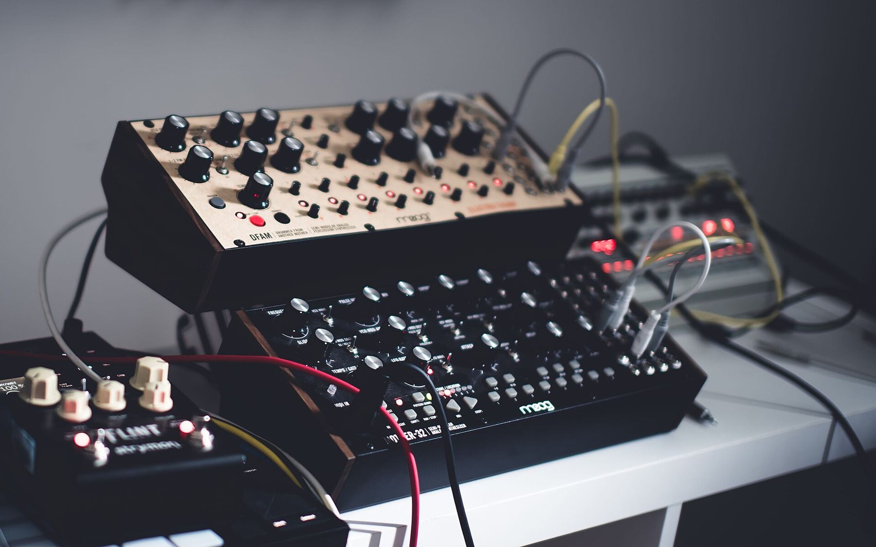 A compact analog synthesizer with patch cables on a studio desk