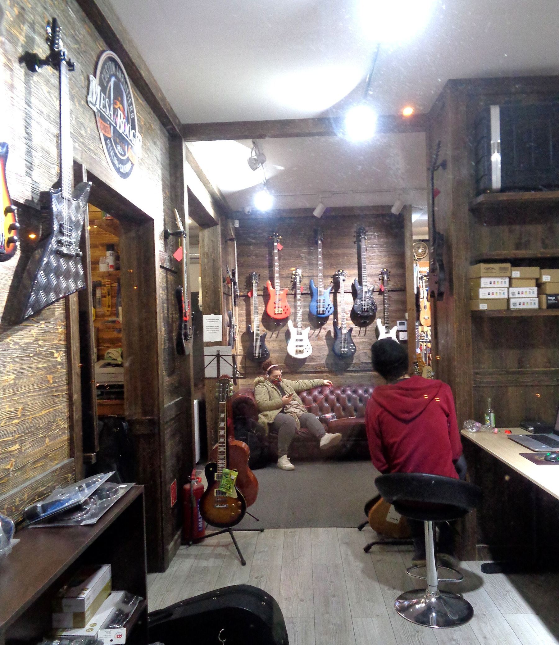 Inside a small instrument shop and service desk with guitars on the walls