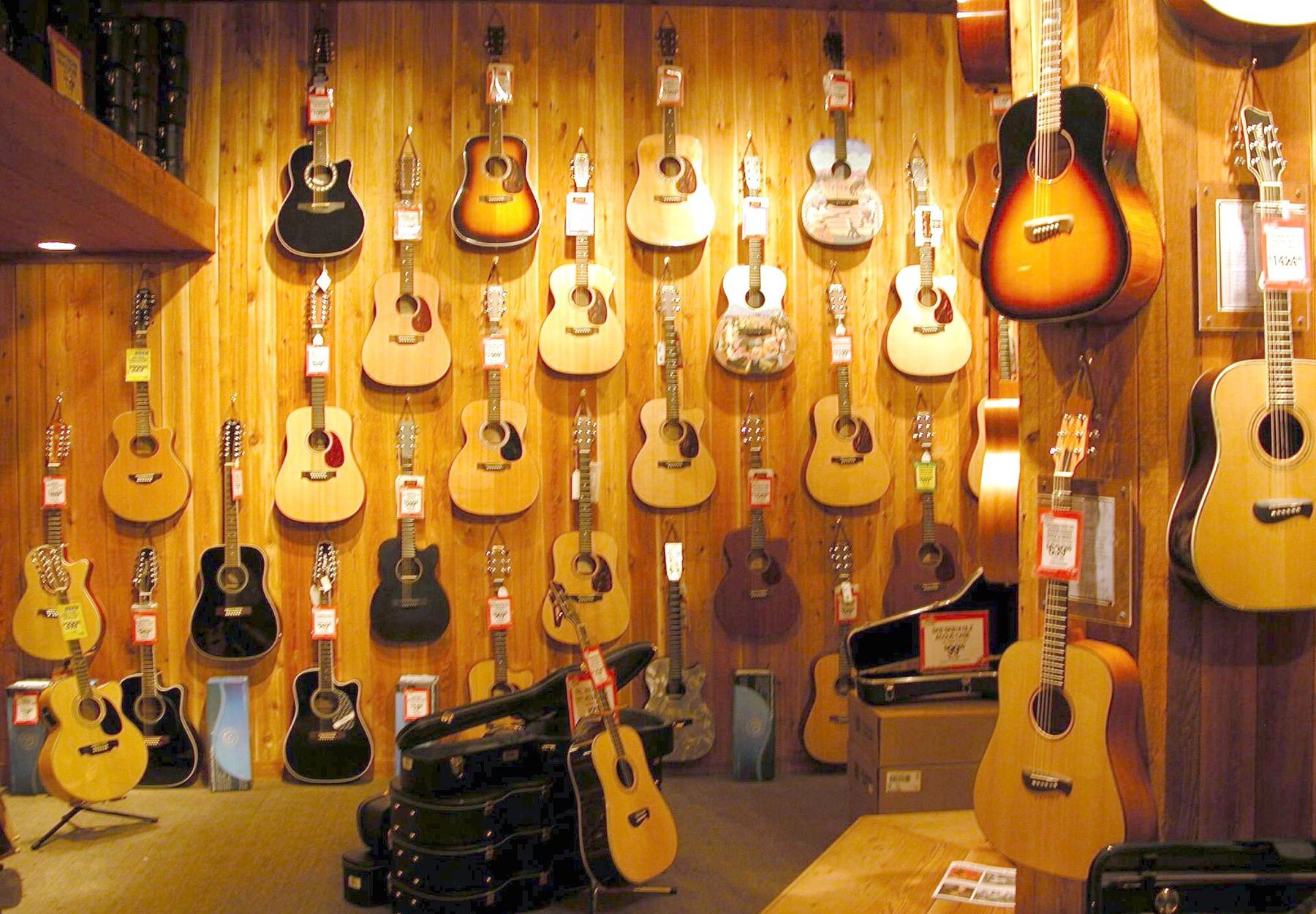 A warm-lit wall of acoustic and electric guitars in a music shop