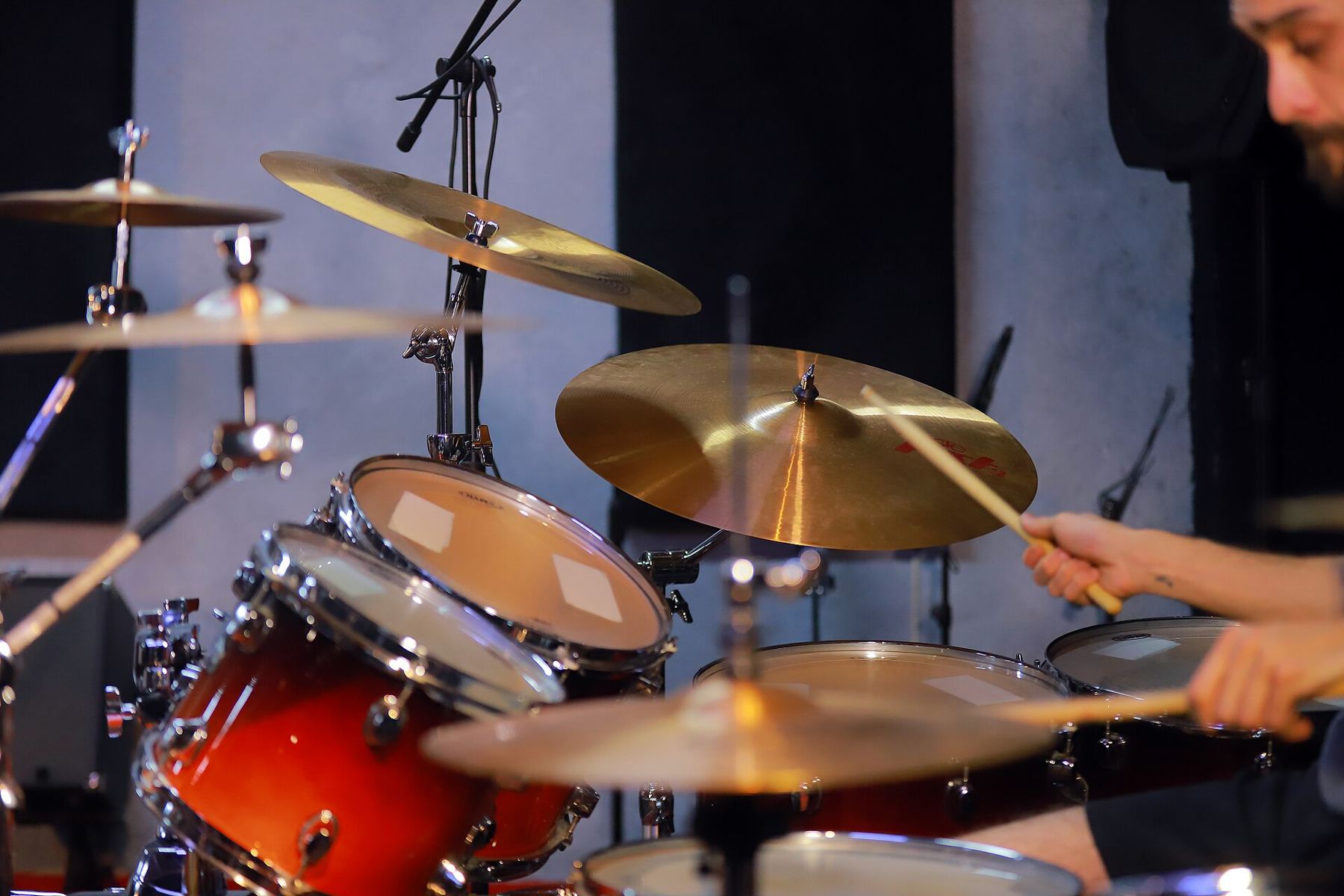 A drummer playing a red kit with several brass cymbals