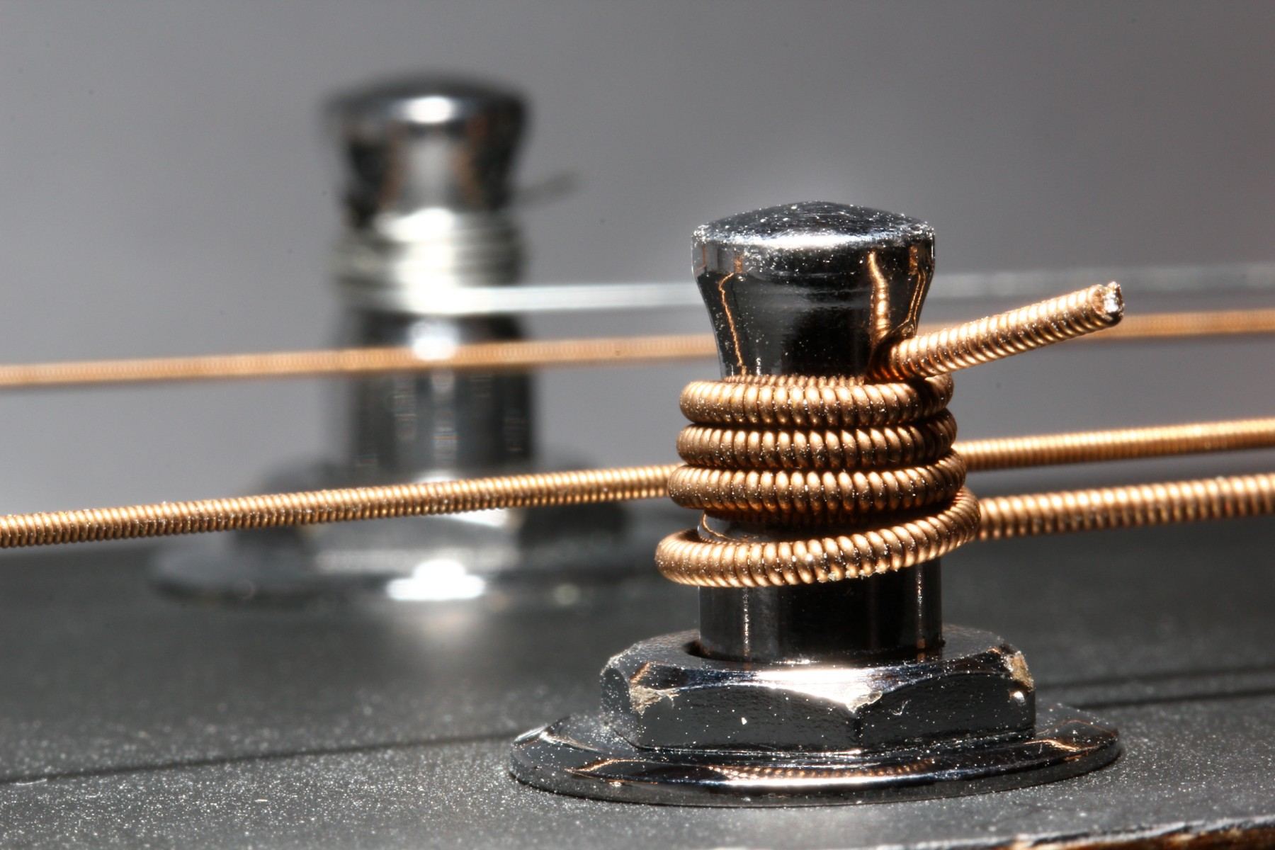 A guitar string wrapped neatly around a chrome tuning post