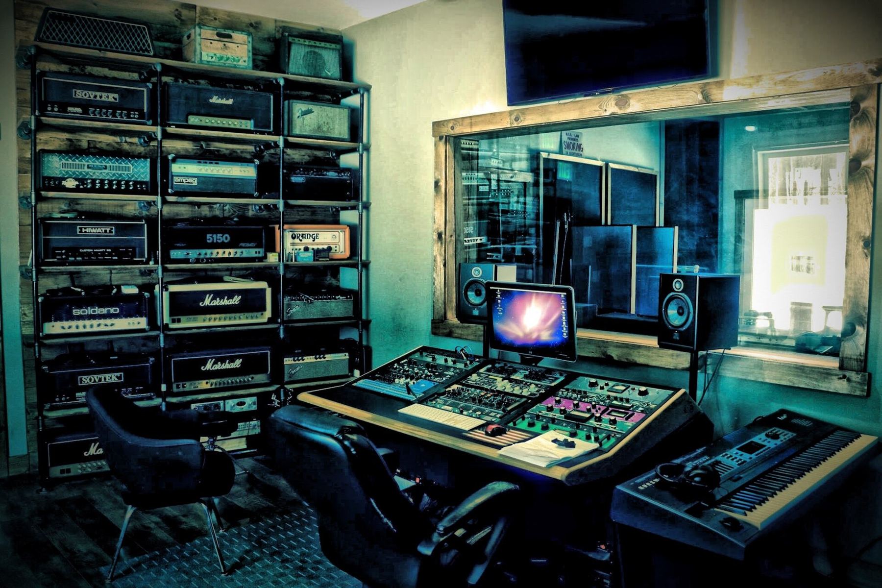 A control room with racks of amplifiers and outboard gear around a mixing desk